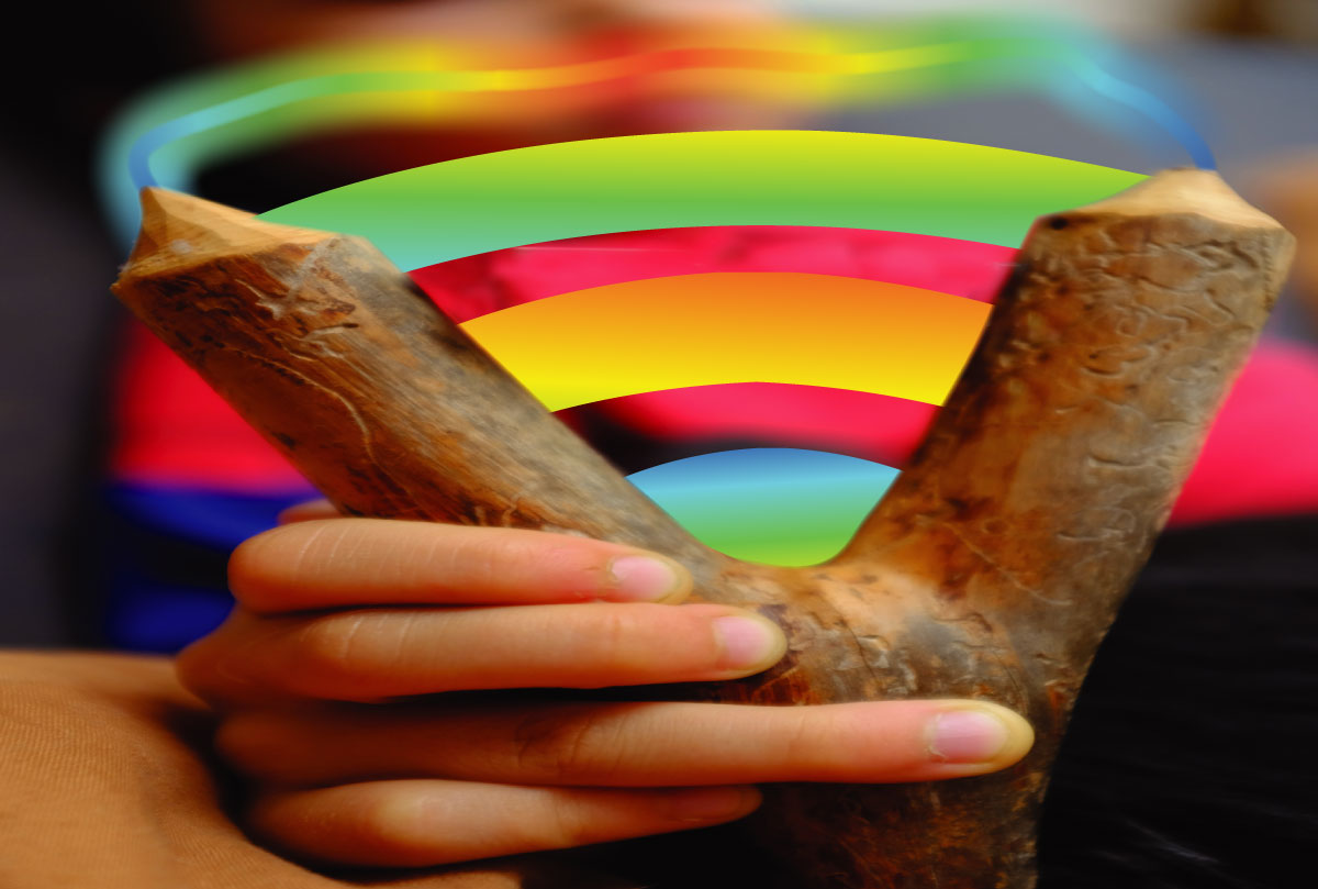 image description: image of a hand holding a carved forked piece of wood from which a colorful wifi signal emerges