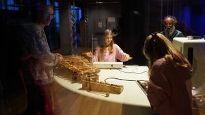 Workshop participants of varying ages are playing with and tuning the specially built instruments by SoundLAB in a sound-insulated glass room.